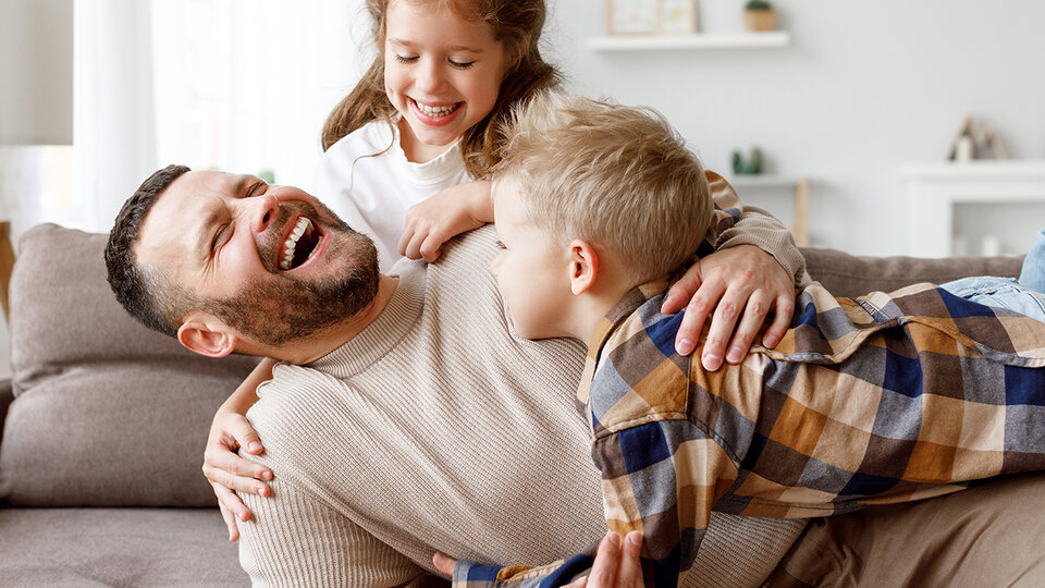 Father and kids laughing on couch